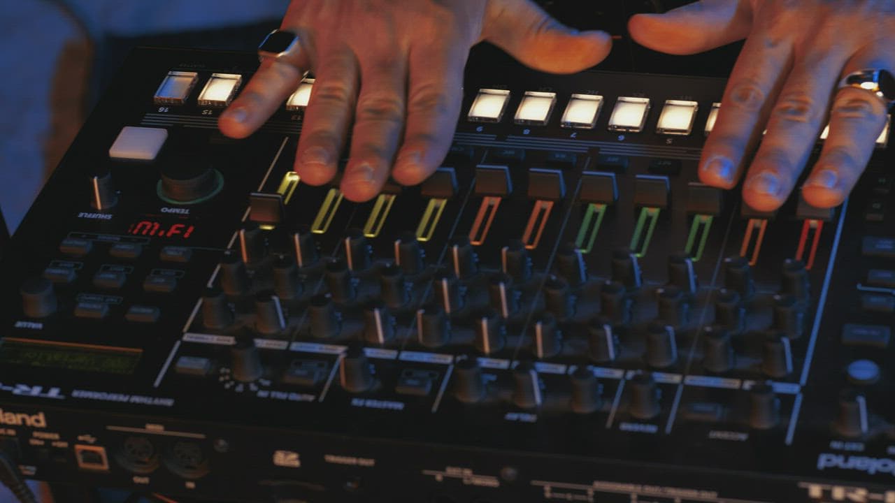 A close-up of DJ mixer controls in low studio light.